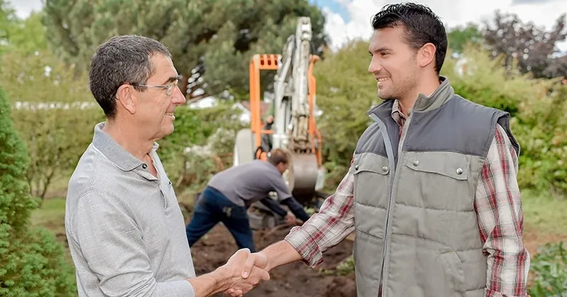 A marketer shaking hands with a landscaper on site